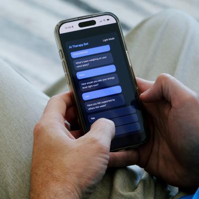 A man having a conversation with an AI therapy bot using a smartphone.