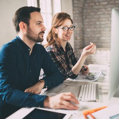 Two colleagues working in front of a computer monitor in an office.