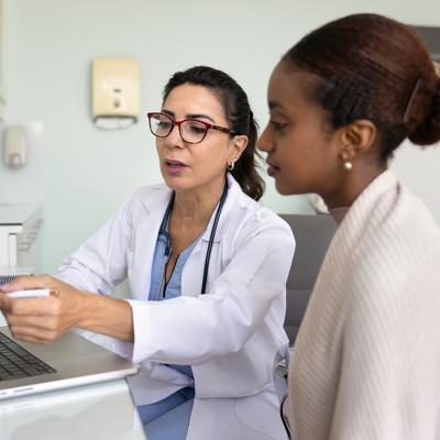 A young black woman going over medical examination results with her female doctor.
