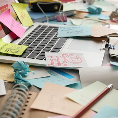 Sticky notes mess on top of a laptop on a working desk.