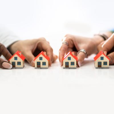 People's hand holding tiny models of houses.