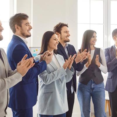 A business team standing and clapping together for a speaker.