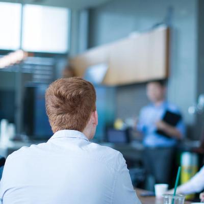 A sales team listening to a presenter in the office.