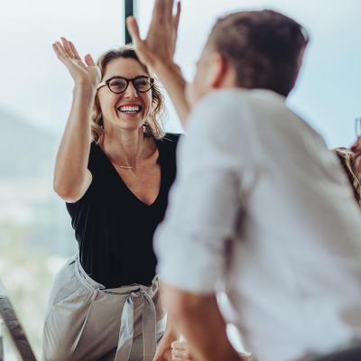 A businesswoman getting a high-five from a colleague.