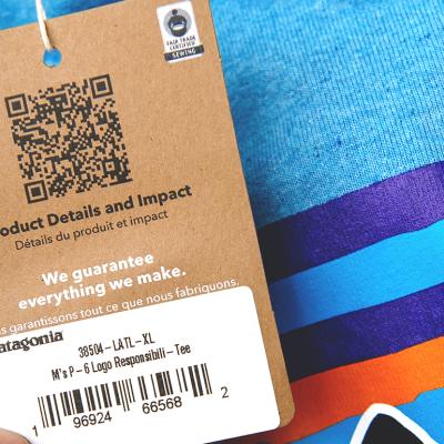 A product tag on a blue clothing shirt with QR code for product details and impact.