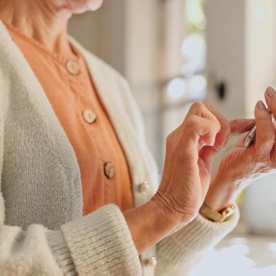 Older woman wearing a peach sweater texting on her phone