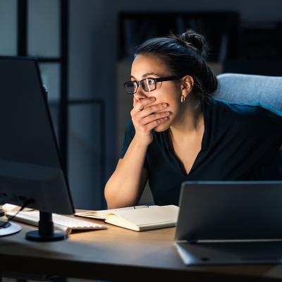 A female employee shocked in front of a computer seeing data hacked.