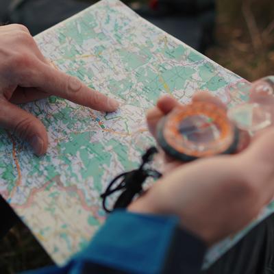 Close up on a traveler's hands navigating a trail map and compass.