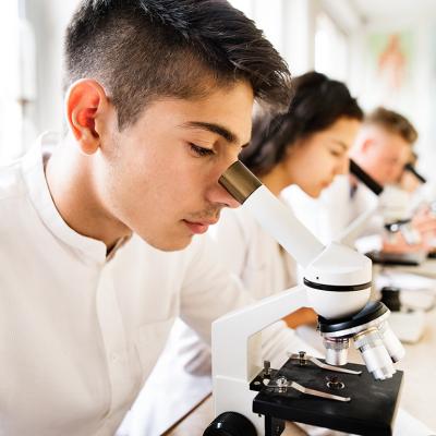 High school students working with microscopes in a laboratory.