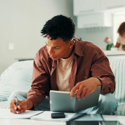 Young man noting expenses and managing finances at home.
