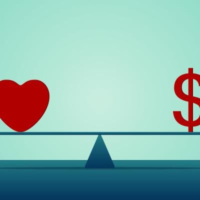 A heart and a dollar symbol on both ends of a seesaw.