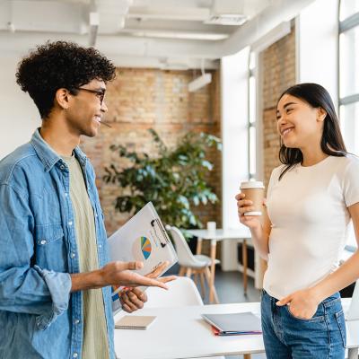 A young man and woman talking in a coworking space.