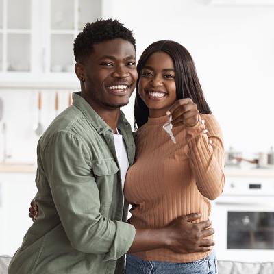 A young black couple happily holding keys to new home.