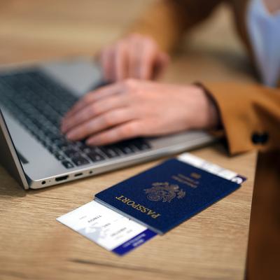 Female traveler using laptop with passport ready at the side while waiting for her flight.