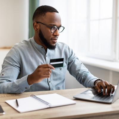A black businessman using credit card to purchase online while in the office.