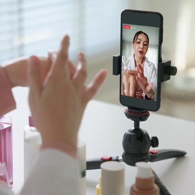 A female vlogger filming a skincare product review using a smartphone on a tripod.