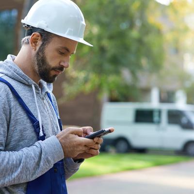 A male construction worker checking phone outdoors.