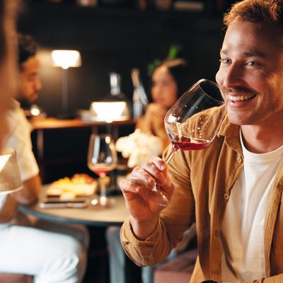 A man facing his date and drinking a glass of wine during their restaurant dinner.