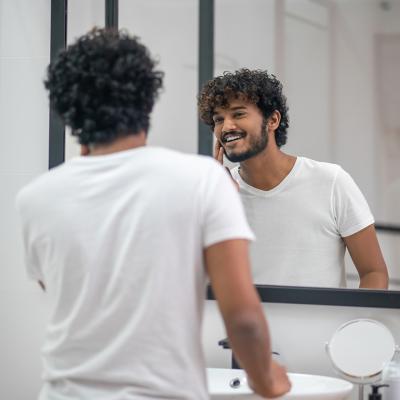 A young man looking at the mirror being pleased with himself.
