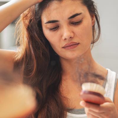 A woman staring at hair loss accumulated in her hairbrush.