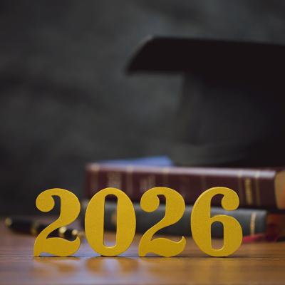 Golden '2026' numbers in front of a stack of books and a graduation cap.