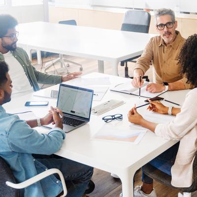 Four members of a business team engaged in a project discussion around a table.