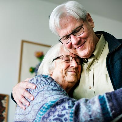 A senior couple dancing together in their home.