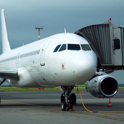 A charter airline airplane parked and connected to a boarding bridge.