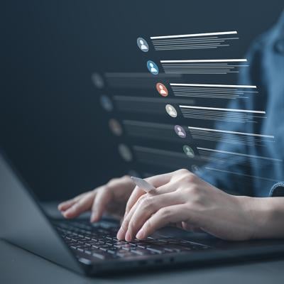 Person typing on a laptop illustrated with a list of contacts software graphics.