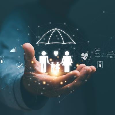 Person's hand holding hologram graphics of a family with an umbrella as a concept of life insurance.