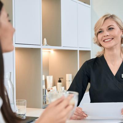 A young woman consulting with a dermatologist at the reception bar of a spa.