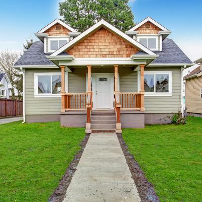 View of a walkway leading to a small house with a porch.