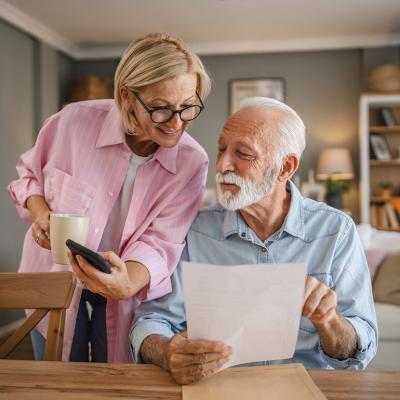 A senior couple reading a document and checking information online together.