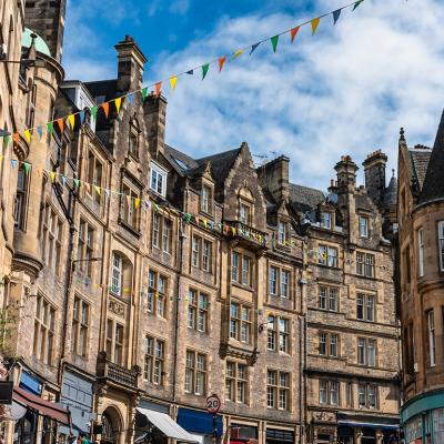 The Old Town street in Edinburgh, Scotland with colorful shops and old stone buildings.