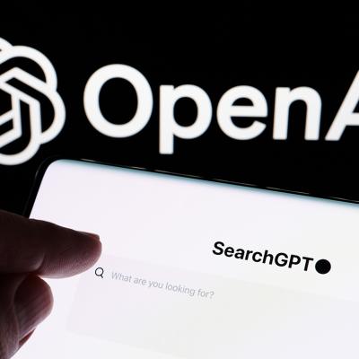 Hand pointing at SearchGPT bar with the logo of OpenAI in the background.