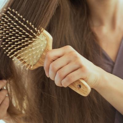 Woman brushing her long hair with a paddle brush.