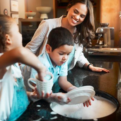 A mother with her two children washing dishes in the kitchen.
