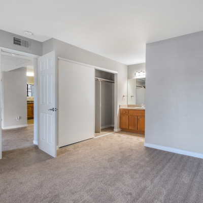 Interior views of an unfurnished apartment unit featuring carpeted bedrooms, built-in vanities, and a gray wall color.