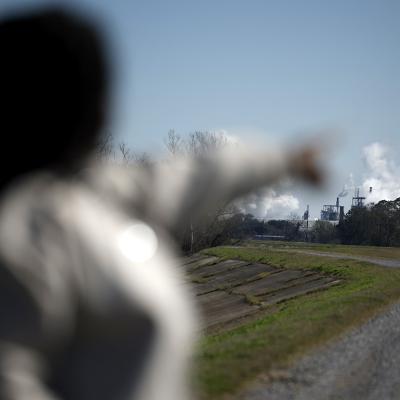 Ashley Gaignard points toward the CF Industries smoke stacks in Donaldsonville, La. That plant emits more air pollutants than all but one other facility nationwide, EPA data show. 