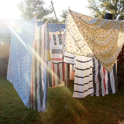 Washed sheets hanging from clothesline to dry under the sun.