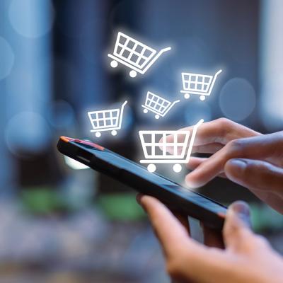 Shopping cart icons over a person using a shopping app on a smartphone.