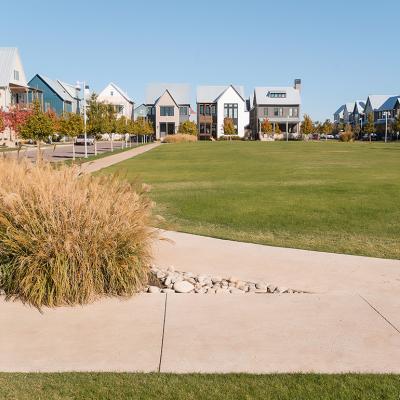 Grassy neighborhood park surrounded by modern homes and sidewalks in Oklahoma City.