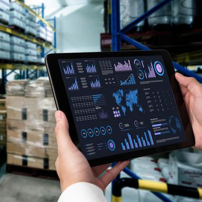 A business data dashboard in an iPad is shown and held by a marketing officer in a stock room.
