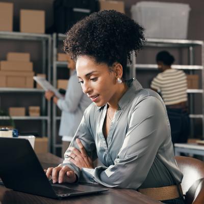 A female businesswoman working with a laptop at a logistics warehouse.