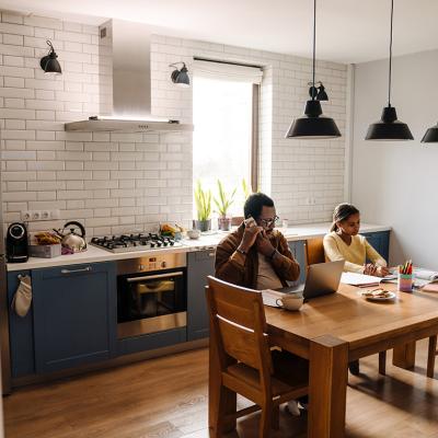 A father talking on the phone while his daughter does homework at home.