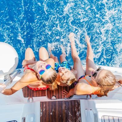 A group of happy friends seated by the platform of a yacht.