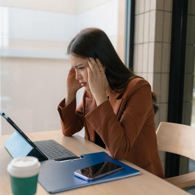 A woman employee who appears to be stressed sits in her workplace desk.