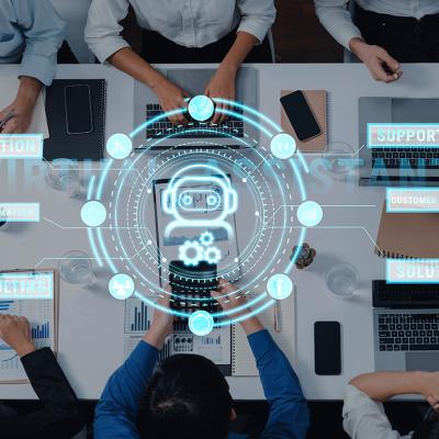 A top view of professionals engaging around a table, while using virtual assistant technology in a meeting.