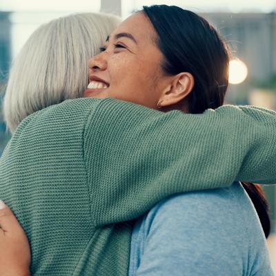 A smiling female staff member sharing a hug with an elderly woman in a physiotherapy place.