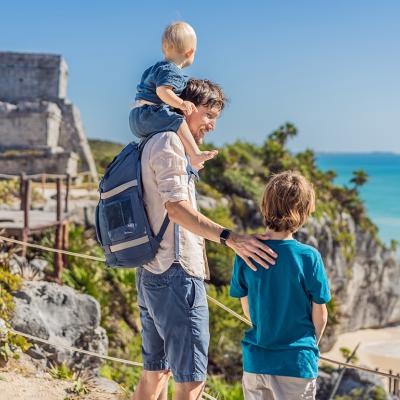 A father with his two sons enjoying the view of the pre-Columbian Mayan walled city of Tulum in Mexico.